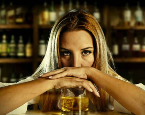 A distressed woman with a drink at a bar.