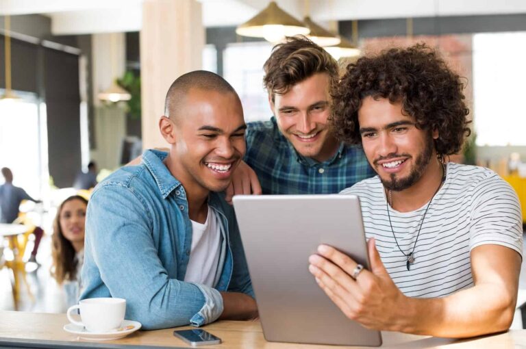 Three young men interacting with a tablet.