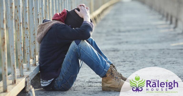 A disheveled young heroin addict in Denver sits on a deserted highway overpass, his head in his hands.