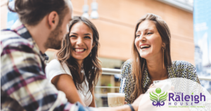 A group of two women and one man have a conversation over coffee.