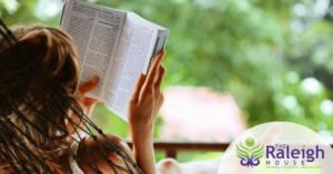 A young woman reads a book in a hammock.