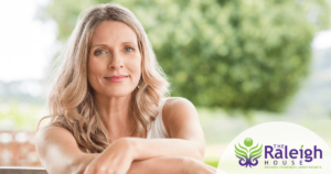 A woman sits in the sun outside, a calm look on her face.