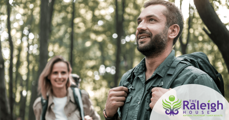 A man and woman go for a hike in the woods, looking peaceful and happy.