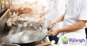 A group of chefs works quickly in a restaurant to prepare entrees.