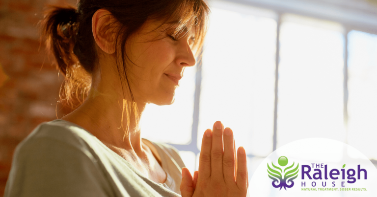 A middle-aged woman closes her eyes with her hands in a prayer pose.