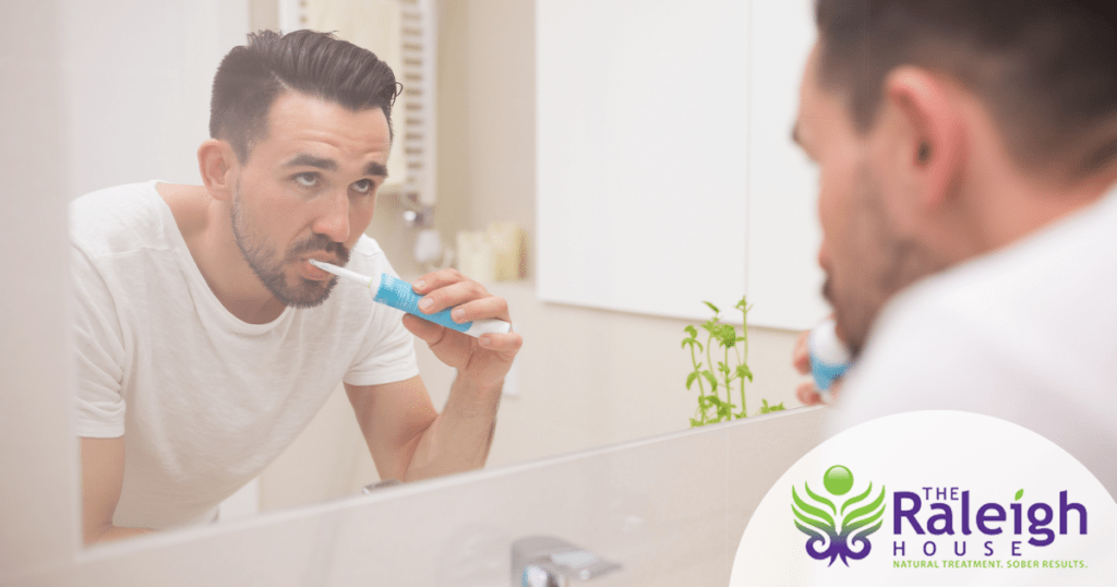 A man looks in his bathroom mirror as he brushes his teeth.