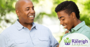 A dad rests his hand on his son’s shoulder as they have a light-hearted talk.