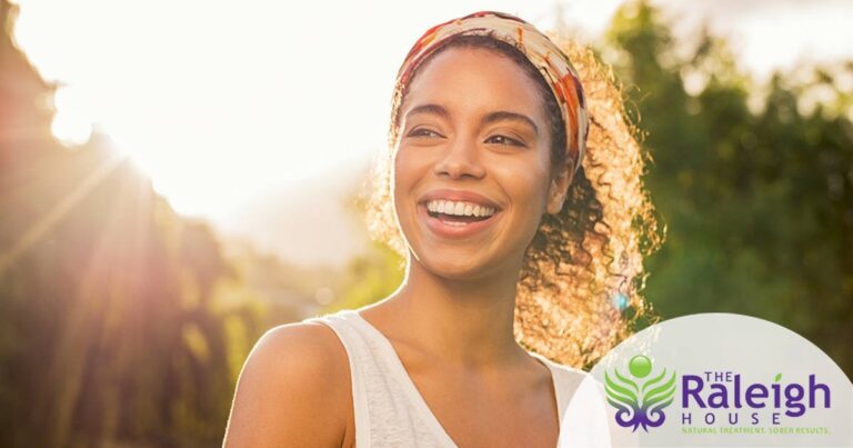 A pretty young woman smiles as the sun shines down on her.