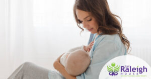 A young mother breastfeeds her infant.