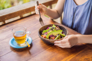 A woman eating a healthy quinoa salad and drinking tea.