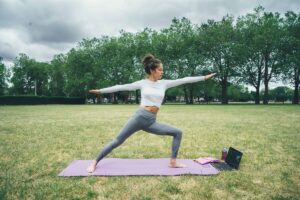 A woman practicing yoga outside at a park.