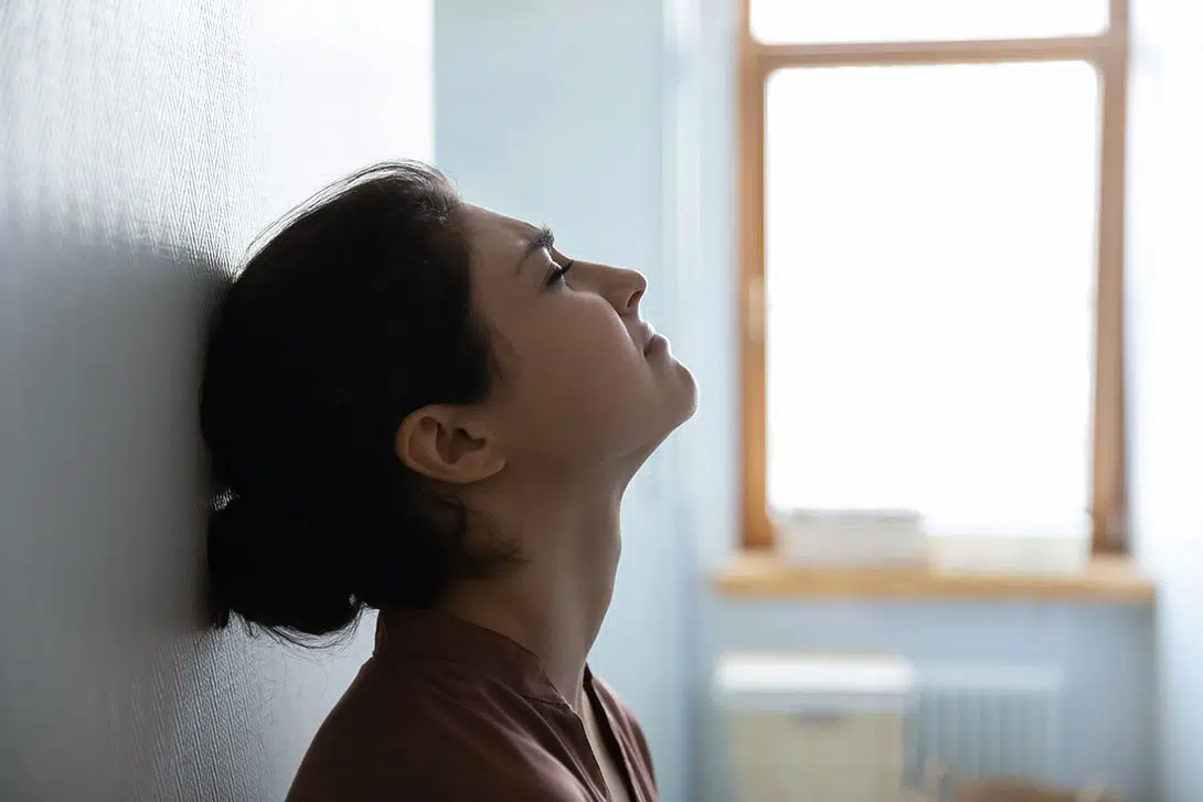 Sad woman sitting against a wall