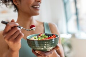 Close up of athletic woman eating a healthy fruit bowl in the kitchen at home