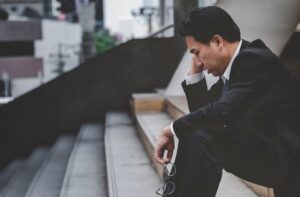 Sad man sitting on steps in business suit